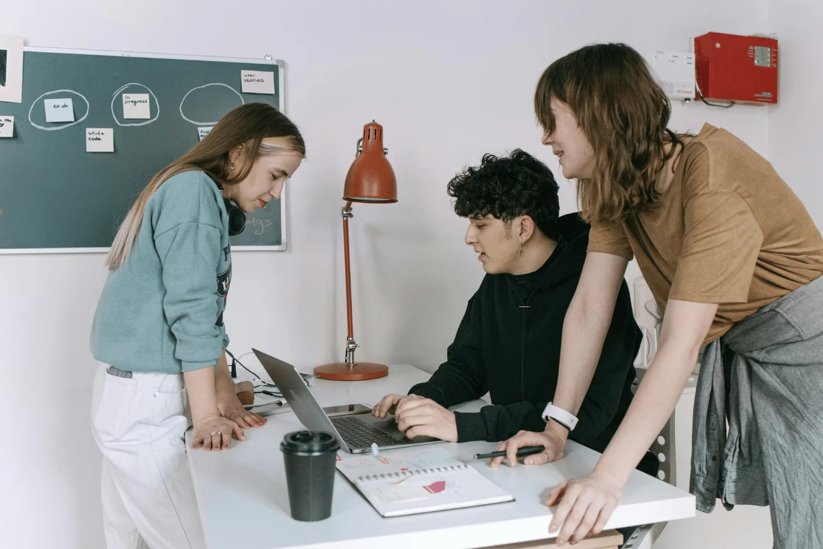 Three colleagues collaborating on a laptop during team meeting.