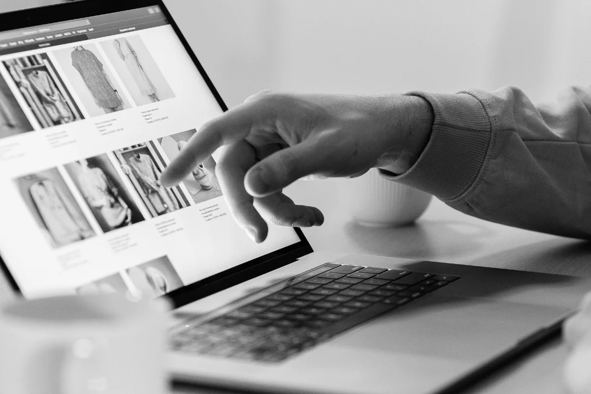 Person browsing online clothing store on laptop with product listings.