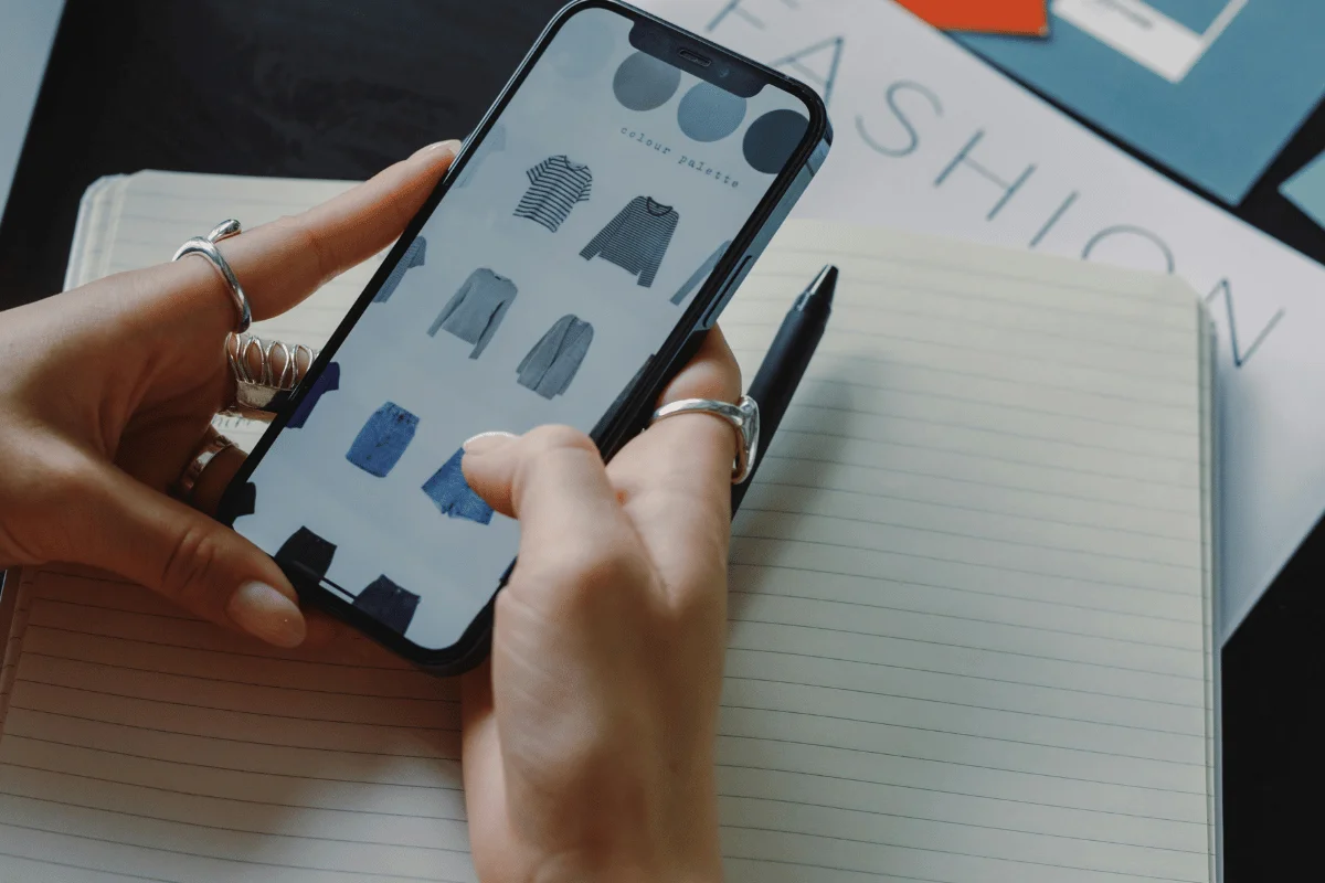 Woman browsing online fashion store on smartphone with clothing options.