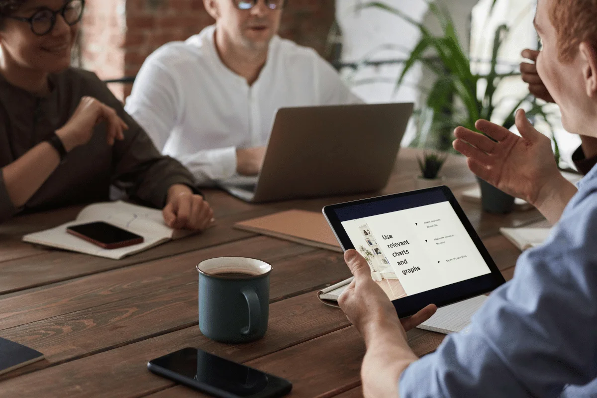 Business meeting with professional showing presentation on tablet screen.