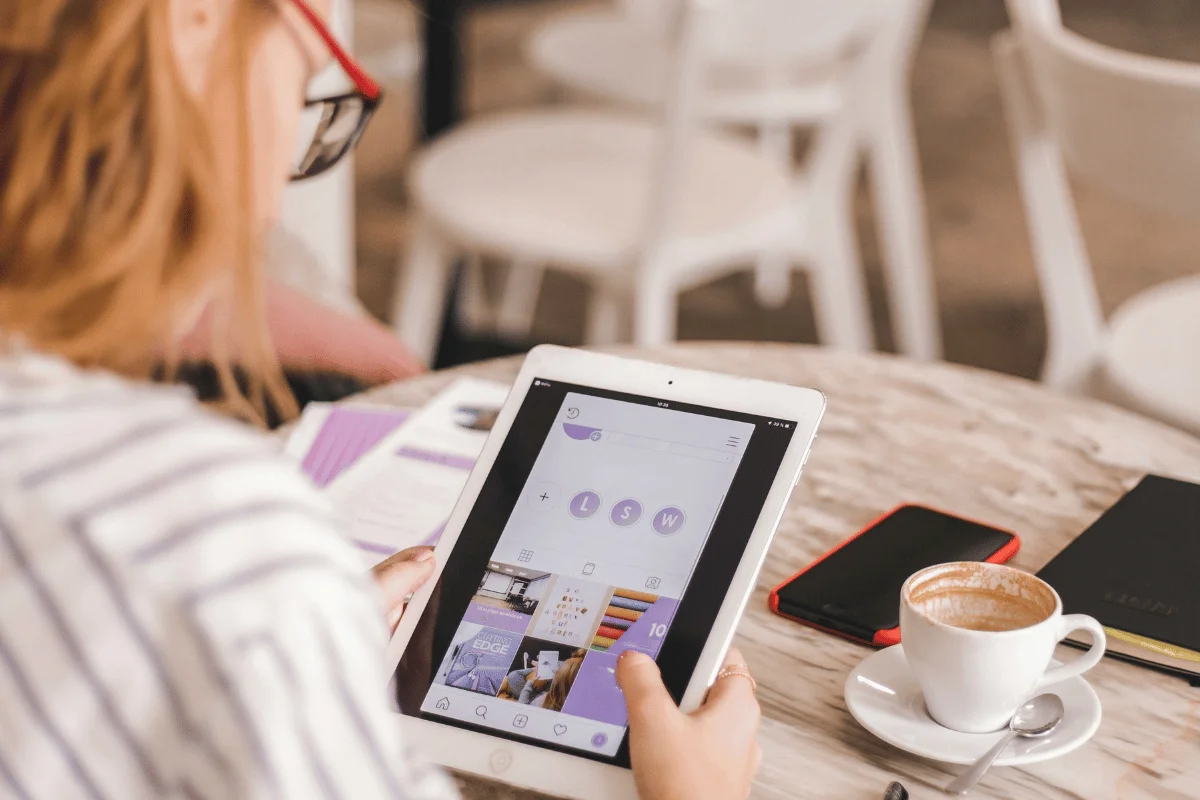 Woman browsing social media on a tablet in a coffee shop.